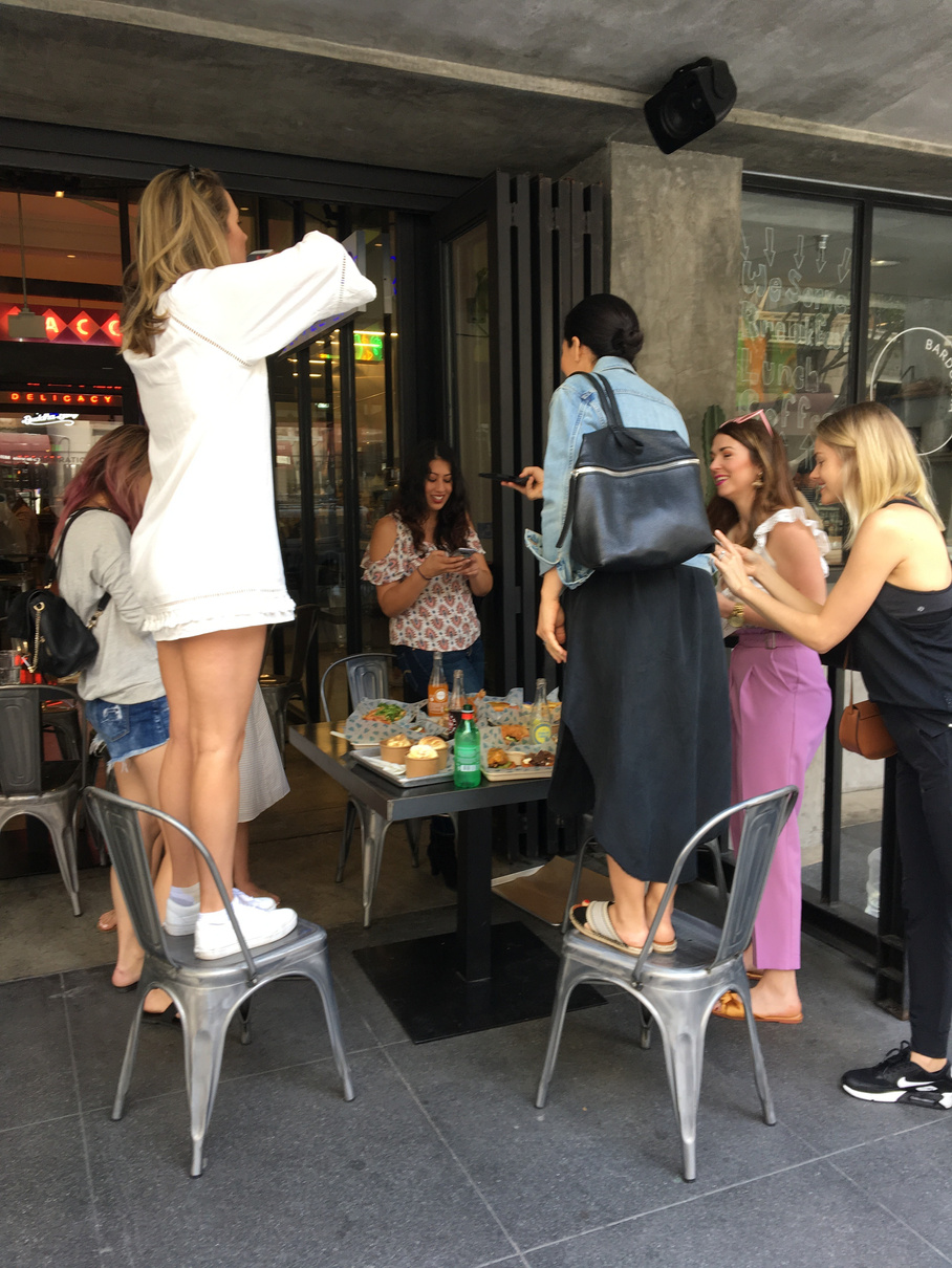 A group of social media influencers taking photos of food on a table as part of an influencer tour of the Los Angeles Fashion District.